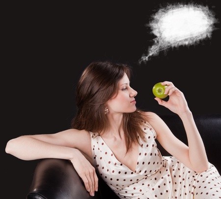 Young beautiful woman hold an apple and dream about somethingの写真素材