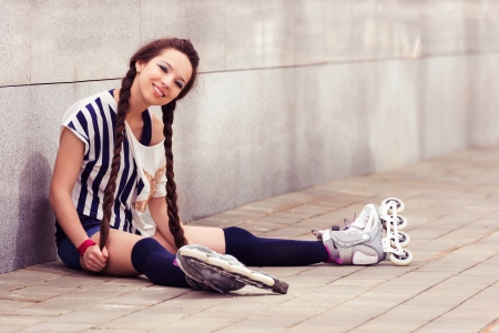 girl on inline skates sitting and resting on a sunny dayの写真素材