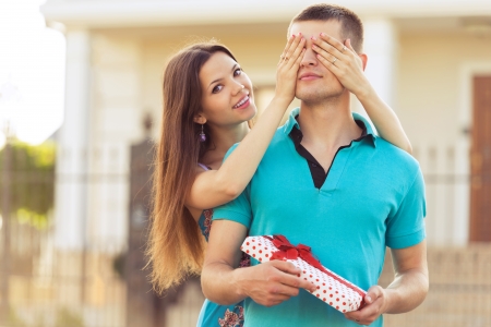 woman covering man's eyes hands. man with giftの写真素材