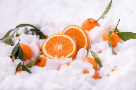 Ripe orange fruits on snow background. And slices orangeの写真素材