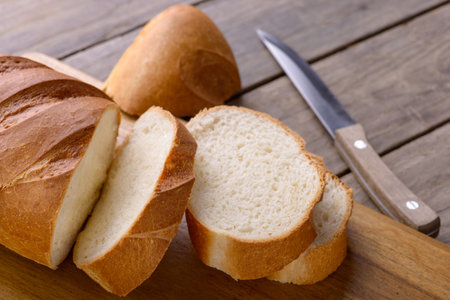 Sliced bread and knife. On wooden table. Closeup