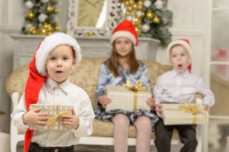 Funny little boy holds Christmas gift. Over background happy kidsの写真素材