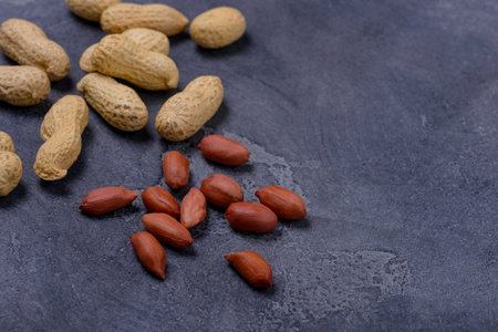 Scattered peanuts on dark background. Copy space for text