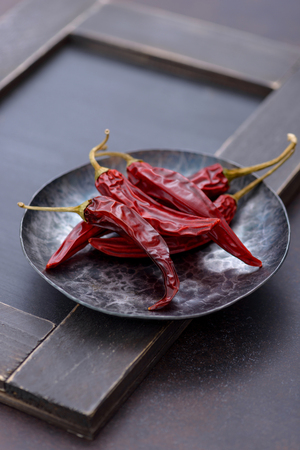 Red dry chilli pepper in plate on wooden backgroundの写真素材