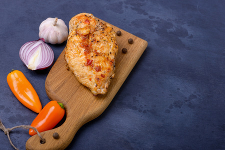 Fried fillet chicken and sweet pepper with onion on cutting boardの写真素材