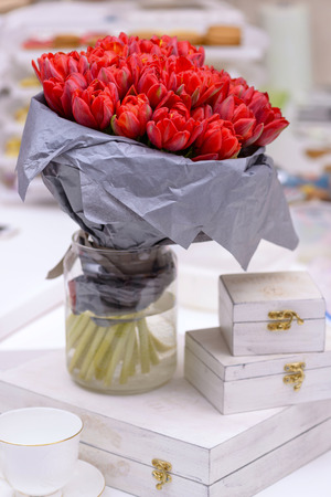 Brightly red bouquet tulips with gift box on tableの写真素材