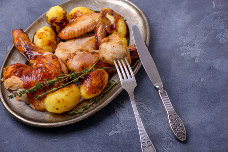 Roasted chicken on plate with cutlery on dark backgroundの写真素材