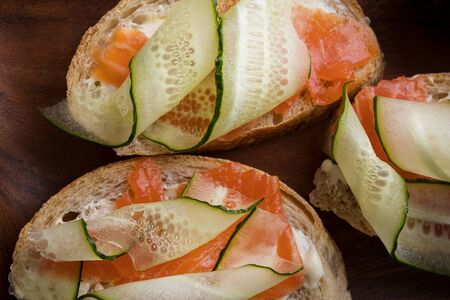 Close-up sandwich with cheese, salmon and cucumber on wooden backgroundの写真素材