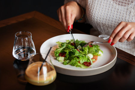 Plate with vegetable vegetarian salad. In the hands of fork and spoon