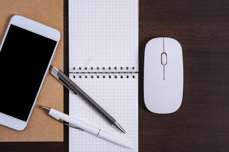 Office table with smartphone and notepad and pens. Top view with copy space