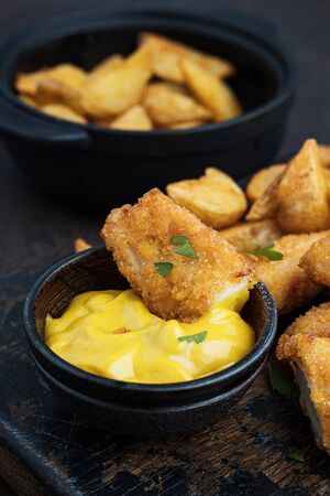 Crispy and spicy chicken with sauce and potatoes on dark tableの写真素材