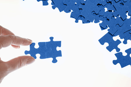 puzzle pieces are scattered on a white background, difficult task, the hand connects the puzzle...