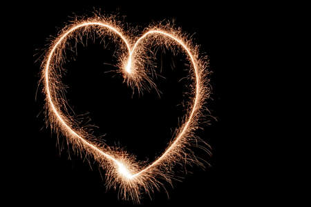 heart drawn with sparklers on a dark background, sparks in the shape of a heart, a symbol of love and happinessの写真素材