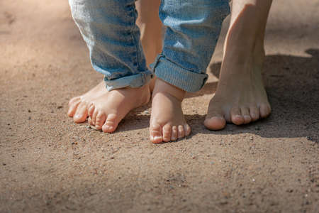 the first steps, the little feet of the baby walk barefoot on the sand, the child learns to walkの写真素材