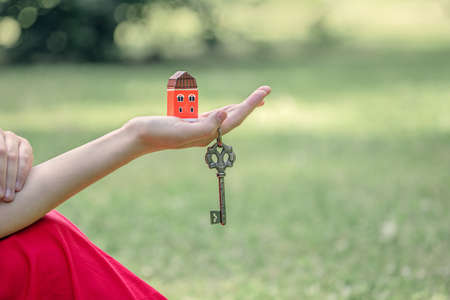 small house in a beautiful female hand, vintage key, the concept of buying your own home, real estate agency, realtor work, home for a happy familyの写真素材