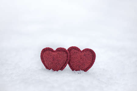 two soft red hearts in white fluffy winter snow, a symbol of love and happinessの写真素材
