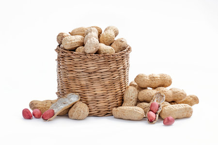 peanuts in a wicker basket, shells and nut kernels on a white background, studio shot