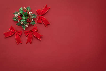 red christmas background with new year decor, bows and wreath in the top left corner, free space for text, mock up for designの写真素材