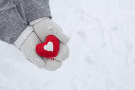 hands in white knitted gloves hold a red heart - a symbol of love and happiness, February 14 Valentine's Dayの写真素材
