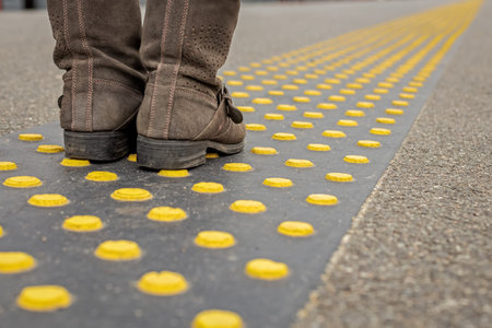 feet in shoes on special traffic signs for blind people in transport, accessible urban environment...