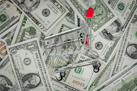 trolley from the supermarket on the background of dollar bills, the concept of finance, money, taxes and bank deposits, investment in the stock marketの写真素材