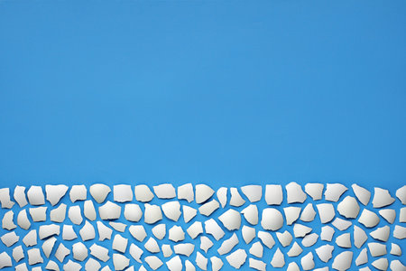 easter background, white eggshell pieces on blue background,