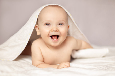 baby laughing in bed after bath or shower, Adorable happy baby in towelの写真素材