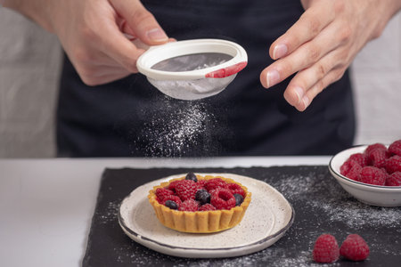 freshly baked homemade pastry, cooking mini cake decorated with fresh summer berries with powder...