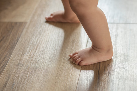 baby's first steps, small children's bare feet walking on the floor close-upの写真素材
