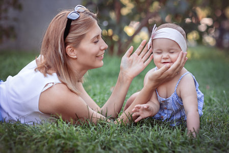 Happy and loving family on vacation. Positive and beautiful woman and her little laughing daughter hugging and lying on the grass on a summer day. Summertimeの写真素材