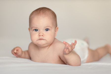 Little adorable newborn infant baby girl lying on tummy and looking in camera, happy tummy timeの写真素材