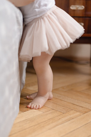 baby feet standing barefoot on wooden floor, baby feet taking first stepsの写真素材
