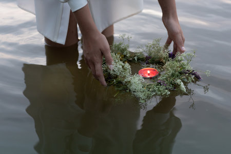 A wreath of flowers with a burning candle floating in water. Russian Slavic tradition, fortune telling on the pagan holiday of Ivan Kupalaの写真素材