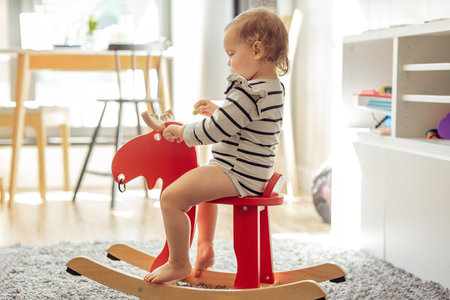 smiling adorable toddler sitting on toy wooden horse, games and development of a 2 year old childの写真素材
