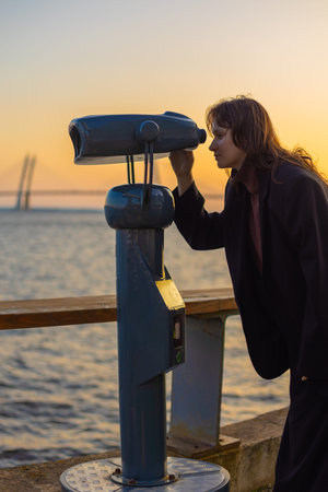 female traveler looks at sights through public stationary binoculars, local tourism, budget trip,...