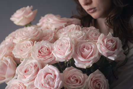 young woman holding a large beautiful bouquet of roses, online flower shop, fresh cut flowers deliveryの写真素材