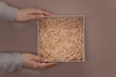 Woman hands holding paper filler top view in cardboard box, Flat lay; top view; empty space for...