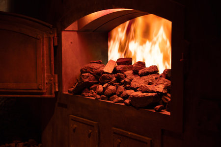 open furnace door in boiler room with flame and pieces of coal, heating with coalの写真素材