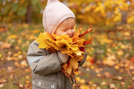 Baby girl enjoying autumn leaves, child having fun with colorful autumn foliageの写真素材
