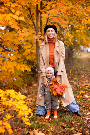 A mother and her baby are walking in the park with a bouquet of autumn leavesの写真素材