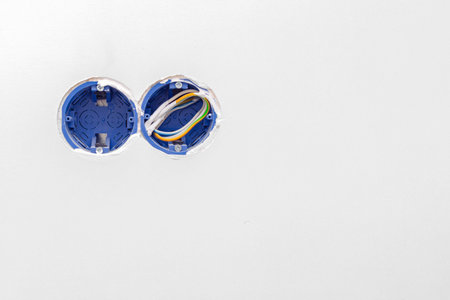 White wall with socket box and wires for outlet or switch installation. Unfinished interior...