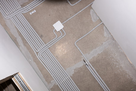 Installation of electrical wiring on the concrete ceiling. Electrical cable system installation. Square ceiling box with plastic corrugated pipes and electric cables. Close-up.の写真素材
