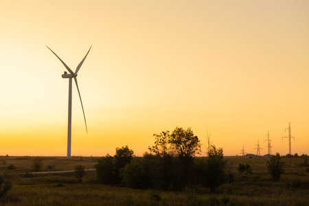 Renewable energy wind turbines in rural area at sunset, large modern propellers generating...