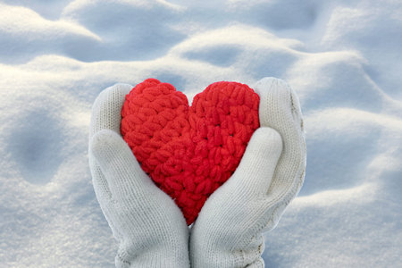 Close-up of hands in mittens holding a handmade heart, Valentine's Day backgroundの写真素材
