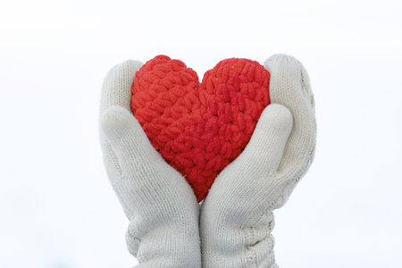 Close-up of hands in mittens holding a handmade heartの写真素材