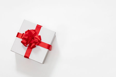white gift box with a red bow on a white background, top view, free space