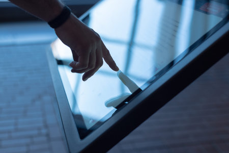 A man uses a multimedia kiosk to search and get information, his finger touching the screen...
