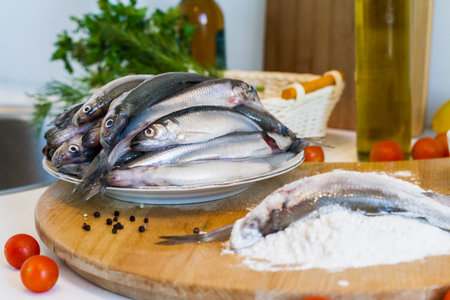 Fresh fish smelt with flour on a cutting board.