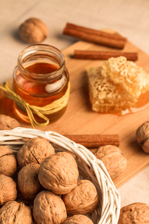 The honey, walnuts and pods of cinnamon lying on a chopping board from a bamboo.の写真素材