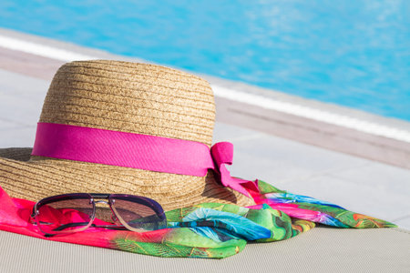 Sun straw hat and sunglasses near the pool.
